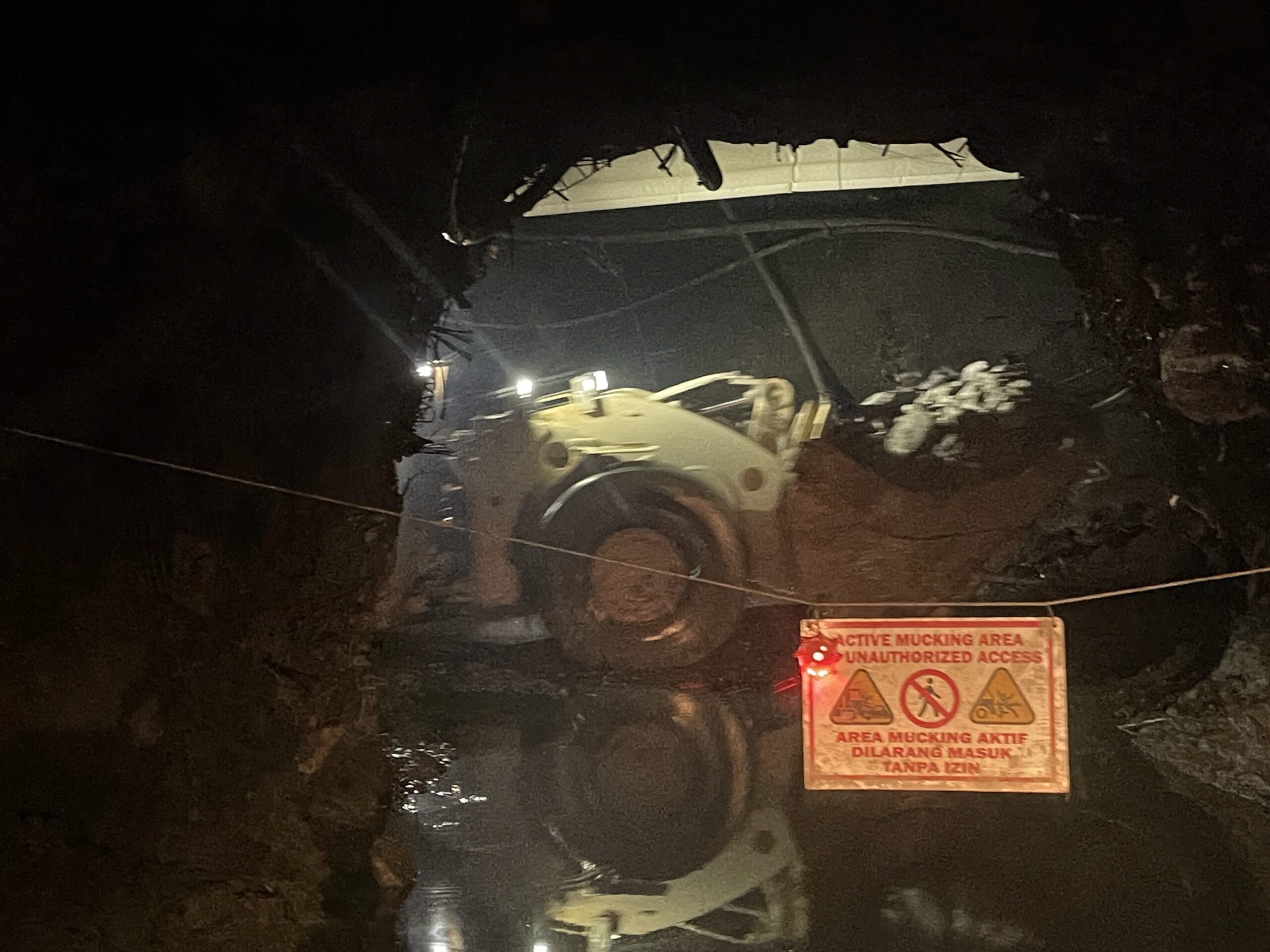 A loader in an active mucking area underground, behind a no-entry sign